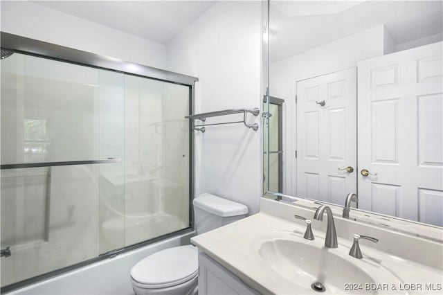 full bathroom featuring combined bath / shower with glass door, vanity, and toilet