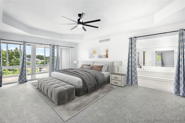 bedroom featuring ceiling fan, light carpet, access to exterior, ensuite bathroom, and a tray ceiling