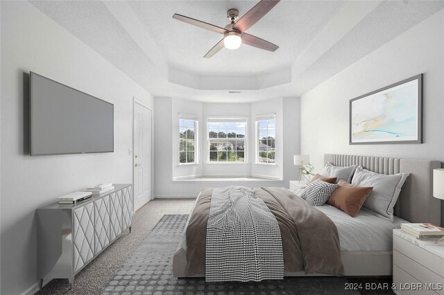 bedroom with light colored carpet, a textured ceiling, ceiling fan, and a tray ceiling