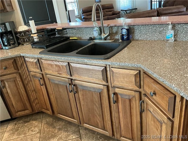 kitchen with light stone countertops, dark tile patterned floors, sink, and a wealth of natural light