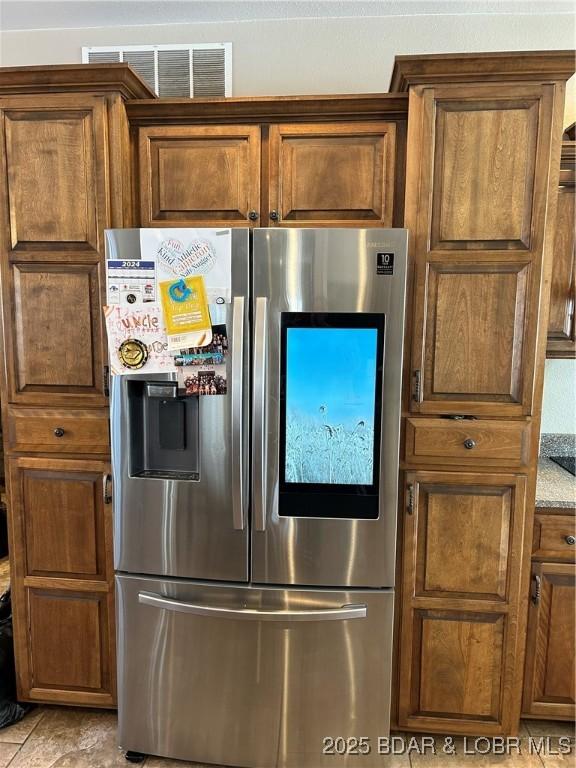 kitchen with light stone counters and stainless steel fridge with ice dispenser