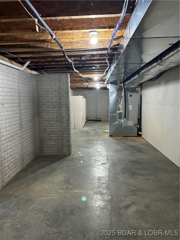 basement featuring heating unit and brick wall