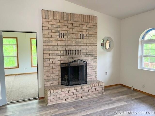 unfurnished living room featuring light wood-type flooring, a fireplace, and vaulted ceiling