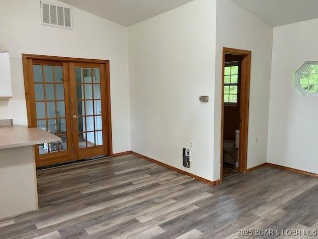 unfurnished dining area featuring vaulted ceiling, dark hardwood / wood-style flooring, and french doors