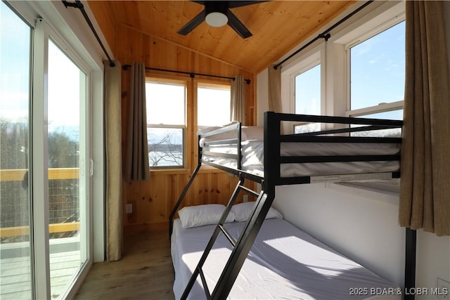 bedroom with wood ceiling, a sunroom, vaulted ceiling, wood walls, and wood finished floors