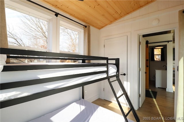 unfurnished bedroom featuring lofted ceiling, wood ceiling, and light wood-style floors