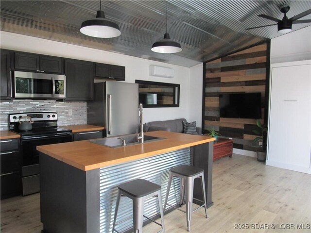 kitchen featuring pendant lighting, sink, stainless steel appliances, a kitchen breakfast bar, and an island with sink