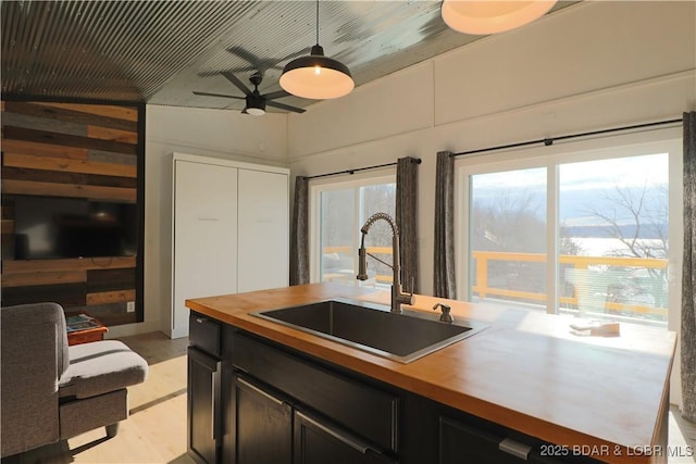 kitchen with hanging light fixtures, a sink, wood counters, and ceiling fan