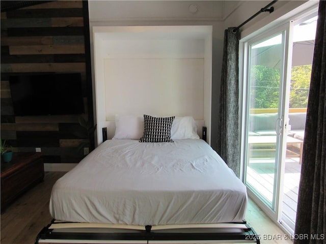 bedroom with access to exterior and wood finished floors