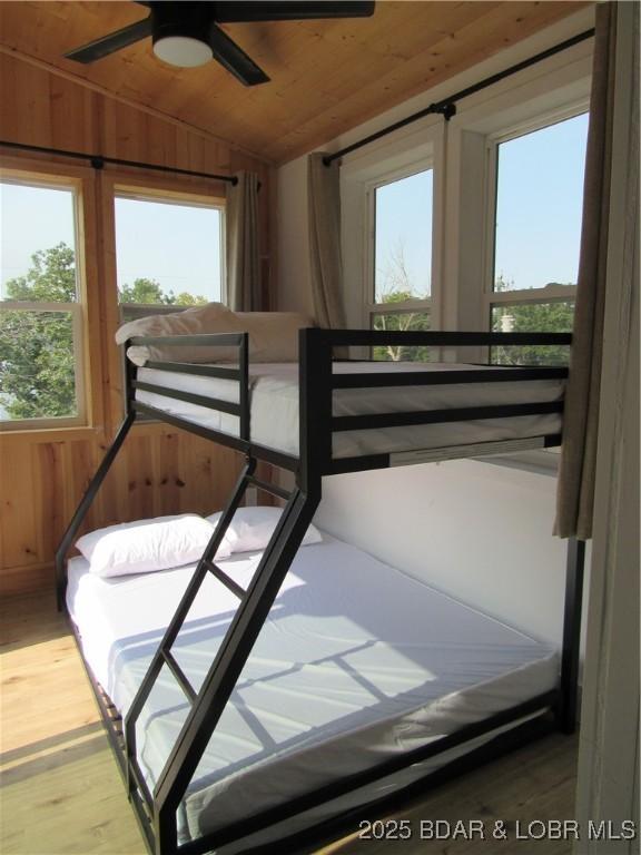 bedroom with wooden ceiling, vaulted ceiling, wood walls, and wood finished floors