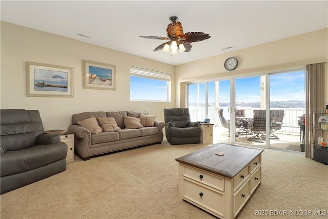 living room with plenty of natural light, light colored carpet, a ceiling fan, and visible vents