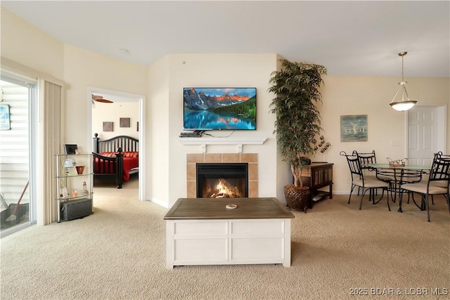 living room with ceiling fan, light colored carpet, and a tiled fireplace