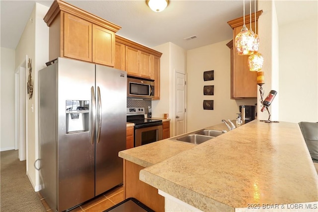 kitchen featuring visible vents, a peninsula, a sink, appliances with stainless steel finishes, and backsplash