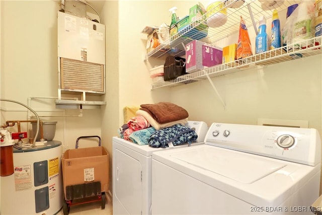 clothes washing area with washing machine and dryer, water heater, and laundry area