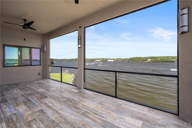 unfurnished sunroom featuring a water view and ceiling fan