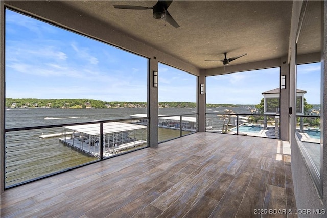 unfurnished sunroom with a water view, plenty of natural light, and ceiling fan