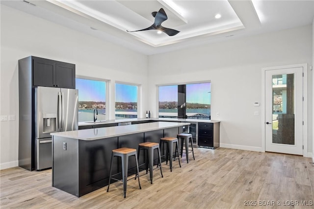 kitchen featuring a kitchen breakfast bar, a center island, stainless steel refrigerator with ice dispenser, and a tray ceiling