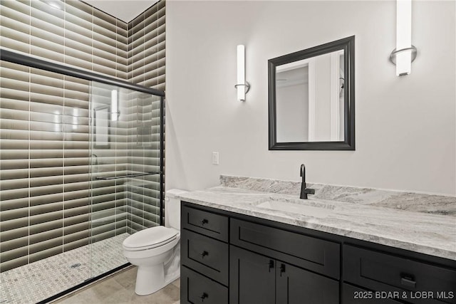 bathroom featuring a tile shower, tile patterned floors, vanity, and toilet