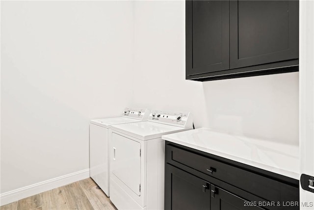 washroom with cabinets, light hardwood / wood-style flooring, and washer and dryer