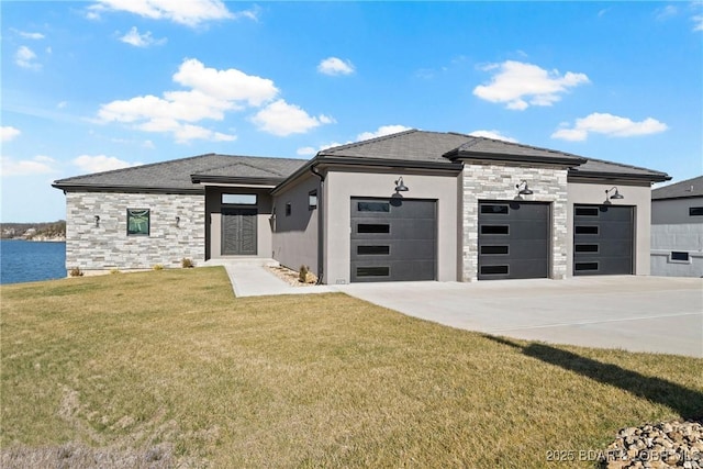 prairie-style house featuring a garage, a water view, and a front lawn