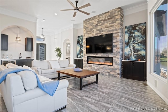 1536 Shootout Dr, Osage Beach, MO 65065 - living room featuring ceiling fan, ornamental molding, arched walkways, and a stone fireplace