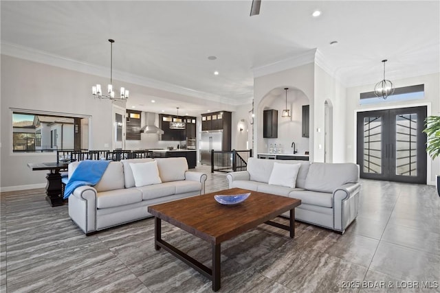 living room featuring sink, french doors, a chandelier, and ornamental molding