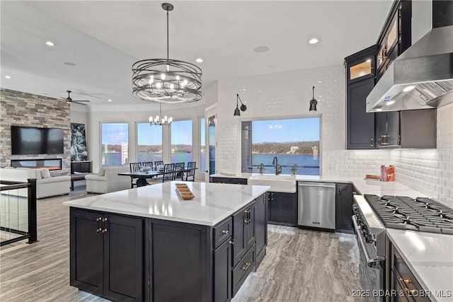 kitchen featuring pendant lighting, a water view, sink, wall chimney exhaust hood, and appliances with stainless steel finishes