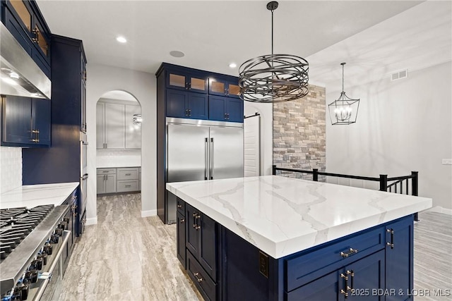 kitchen with a center island, blue cabinets, hanging light fixtures, light stone counters, and a chandelier