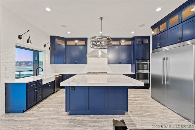 kitchen featuring blue cabinetry, stainless steel appliances, light stone counters, and hanging light fixtures