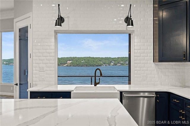 kitchen featuring dishwasher, backsplash, a water view, sink, and light stone counters