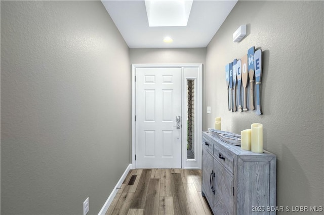 doorway to outside with light wood-type flooring and a skylight