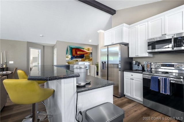 kitchen with lofted ceiling with beams, white cabinetry, appliances with stainless steel finishes, and a kitchen island