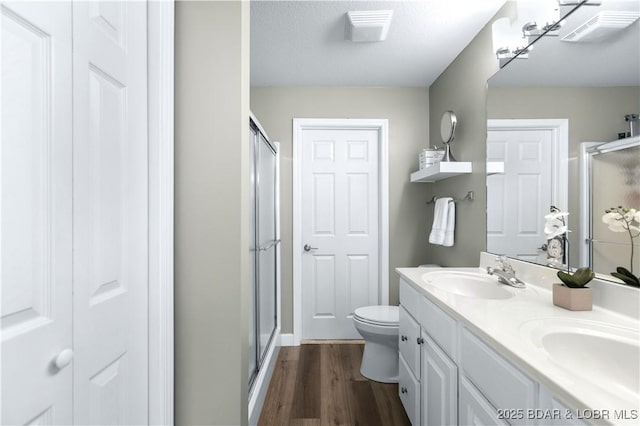 bathroom with a shower with door, wood-type flooring, vanity, and toilet