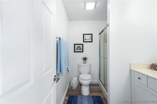 bathroom featuring vanity, hardwood / wood-style flooring, a shower with shower door, and toilet