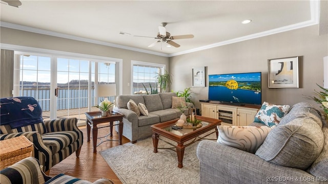 living room with hardwood / wood-style floors, ceiling fan, a water view, and crown molding