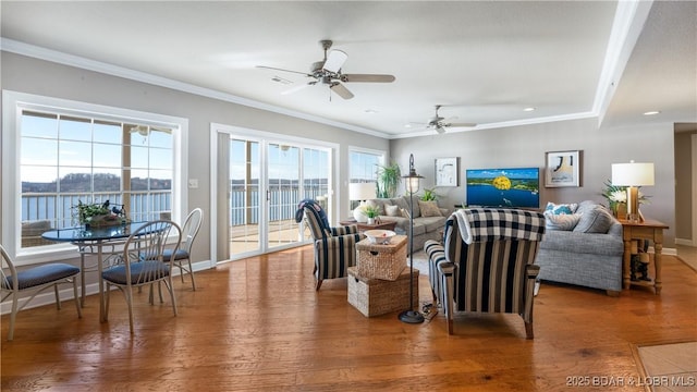 living room with hardwood / wood-style flooring, ceiling fan, ornamental molding, and a water view