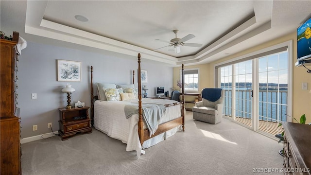 carpeted bedroom featuring ceiling fan, access to outside, and a tray ceiling