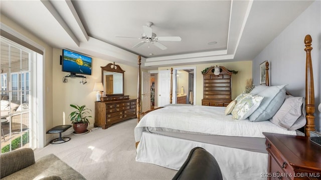 carpeted bedroom with ceiling fan, a raised ceiling, and ensuite bathroom