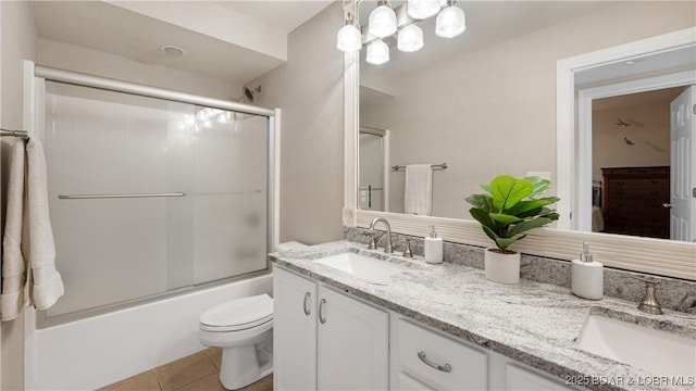 full bathroom with toilet, vanity, tile patterned floors, and bath / shower combo with glass door