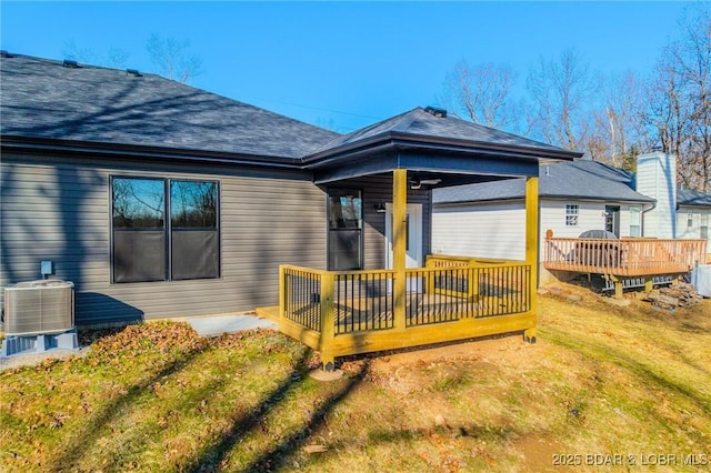 rear view of house with a yard, a wooden deck, and central air condition unit