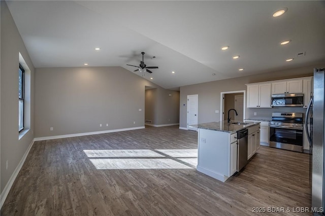 kitchen with stone counters, white cabinetry, sink, stainless steel appliances, and an island with sink