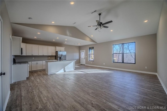 kitchen with hardwood / wood-style floors, a kitchen island with sink, white cabinets, ceiling fan, and stainless steel fridge