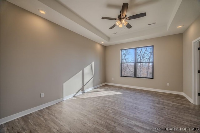 empty room featuring hardwood / wood-style floors, a raised ceiling, and ceiling fan