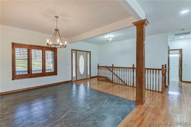 entryway with dark wood-type flooring, decorative columns, and a notable chandelier