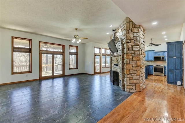 unfurnished living room with a fireplace, a textured ceiling, and ceiling fan