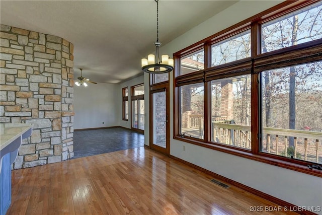 unfurnished living room with hardwood / wood-style floors and ceiling fan with notable chandelier