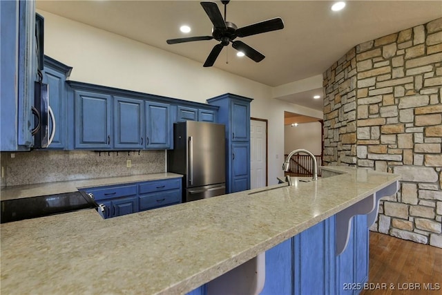 kitchen with blue cabinetry, kitchen peninsula, and stainless steel appliances