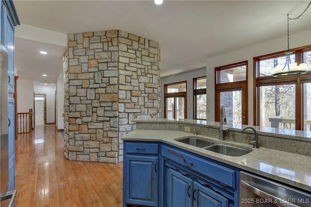 kitchen featuring stainless steel dishwasher, blue cabinets, sink, light hardwood / wood-style floors, and hanging light fixtures