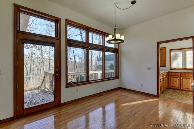 unfurnished dining area with light hardwood / wood-style flooring and an inviting chandelier