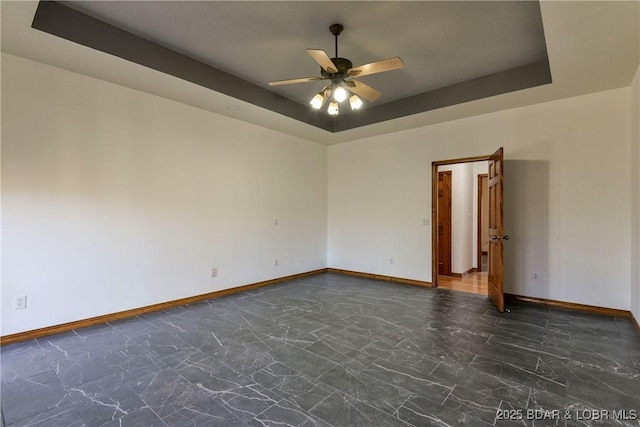 empty room featuring a tray ceiling and ceiling fan